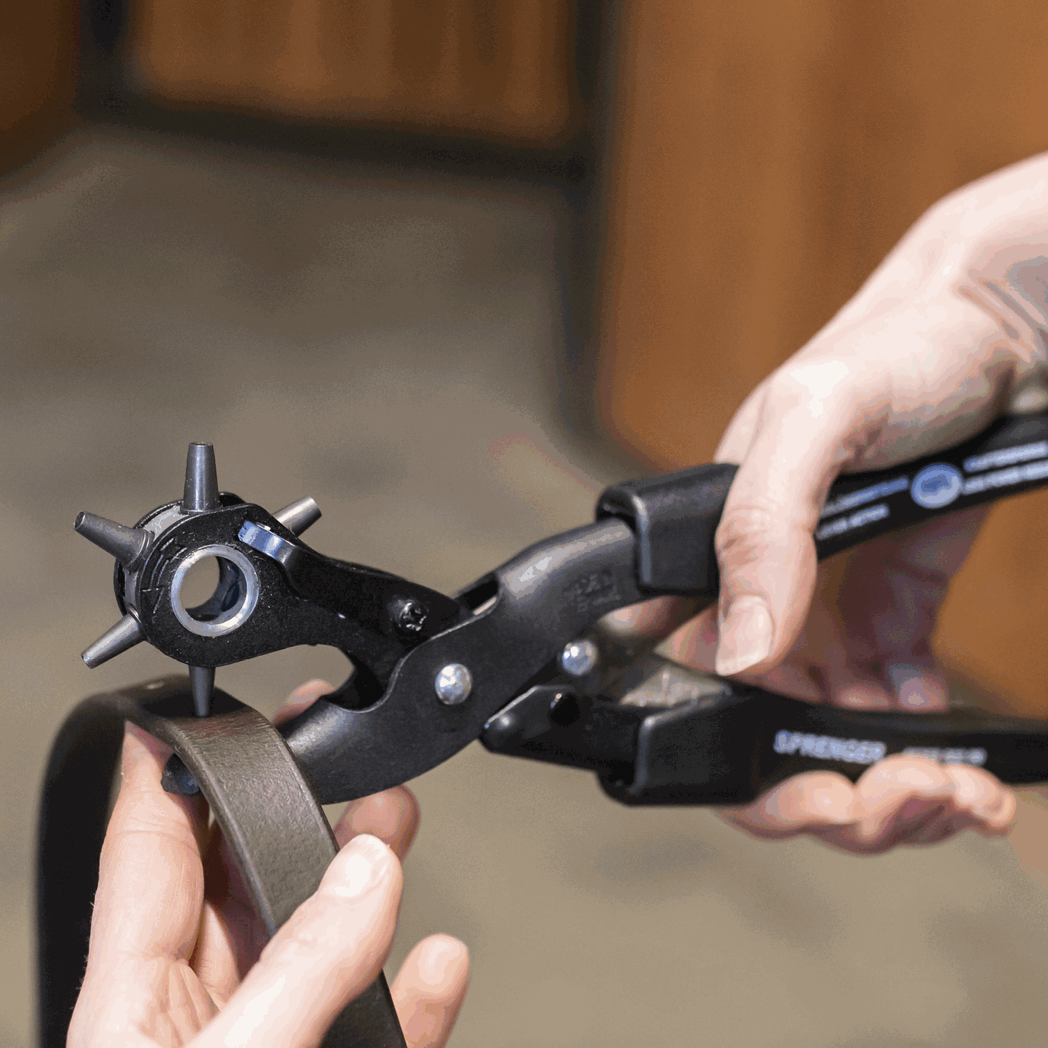 Person using a herm sprenger leather hole punch tool on a piece of leather.