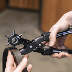 Person using a herm sprenger leather hole punch tool on a piece of leather.