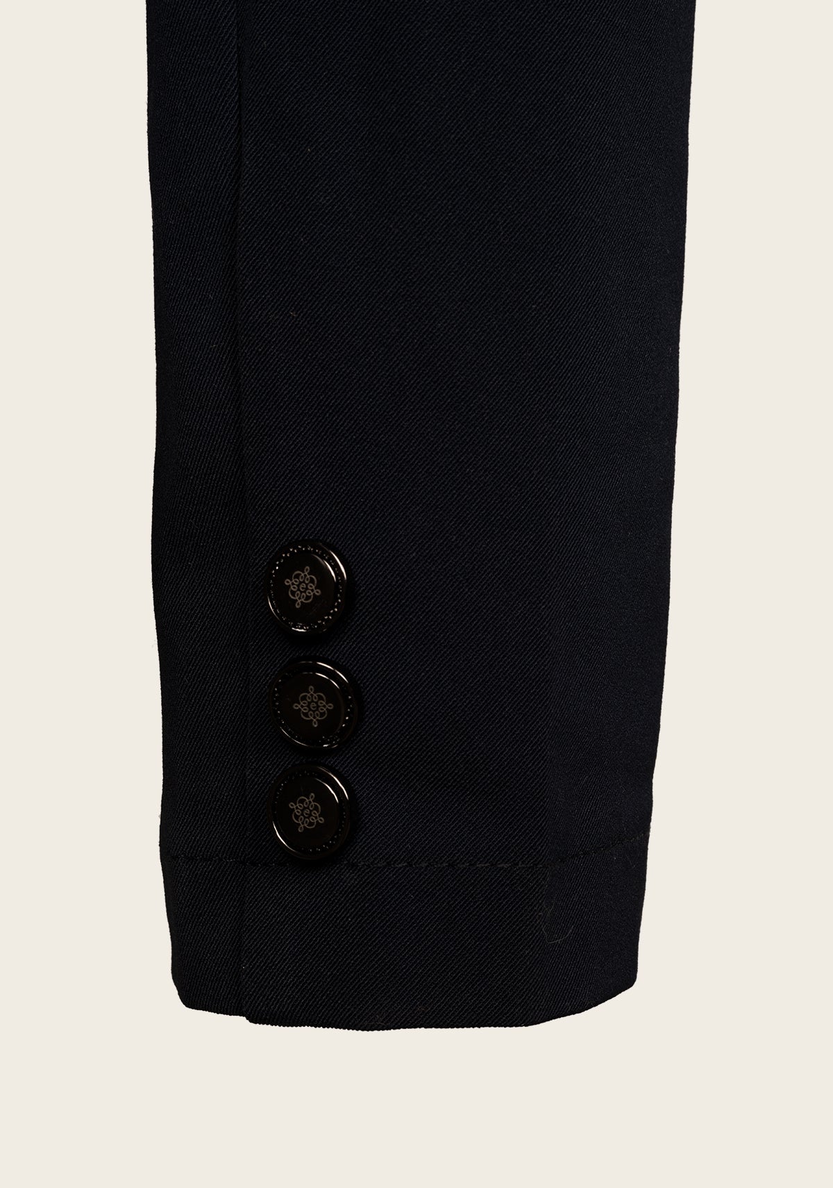 Close-up of Espoir show jacket cuff with custom gold button and fine stitching on lightweight stretch fabric.