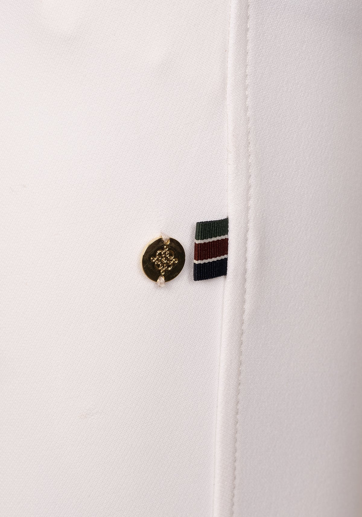 Detail view of Espoir Bamboo Breech signature crossed back belt loop in brand colors, emphasizing craftsmanship and equestrian identity.