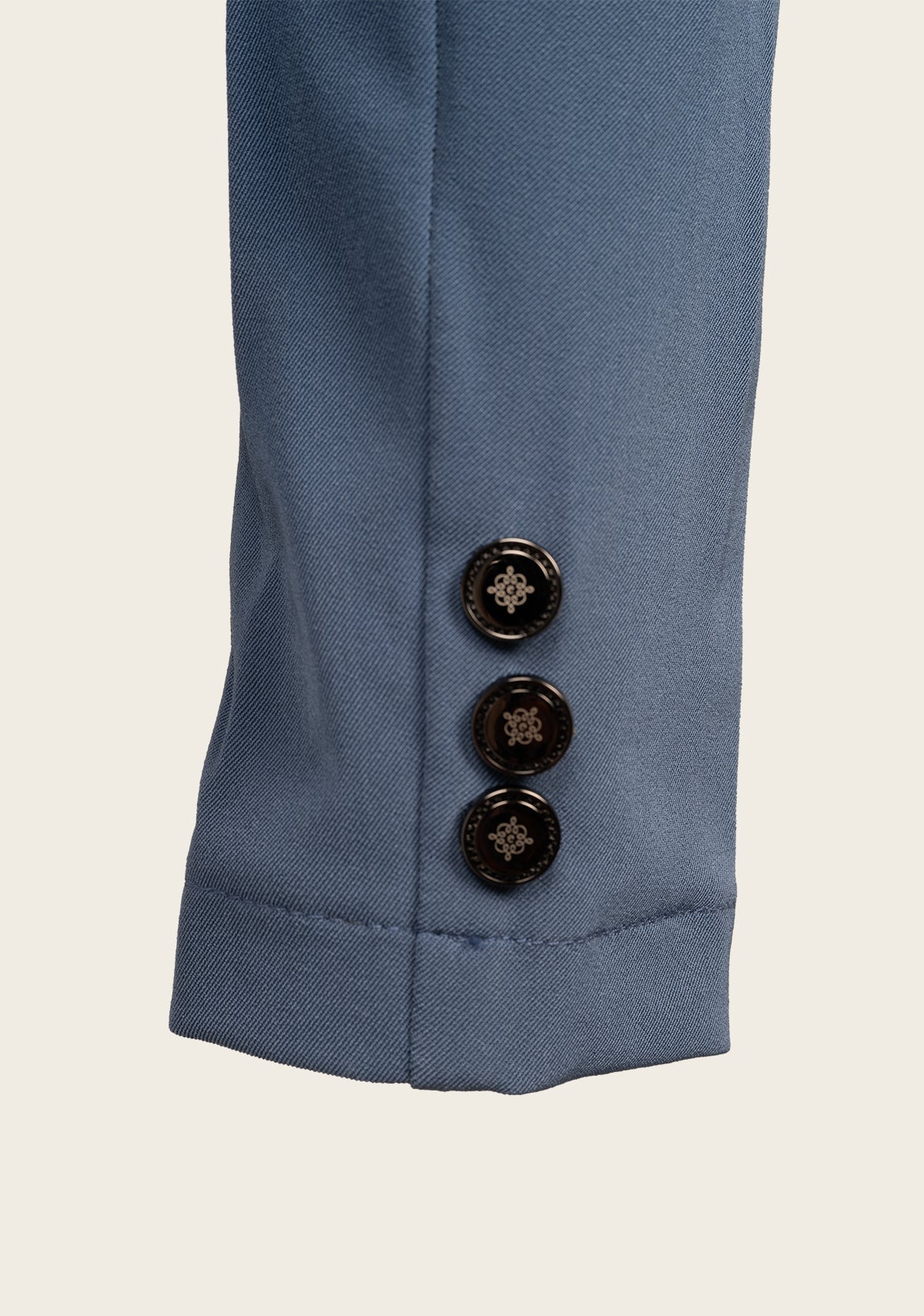 Close-up of Espoir show jacket cuff featuring custom gold button and fine stitching on lightweight stretch fabric.