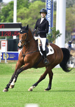 Show jumper riding a horse while wearing Espoir show jacket, showcasing athletic fit, flexible fabric, and elegant competition styling
