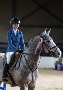 Equestrian rider wearing Espoir show jacket while sitting on a gray horse, showcasing athletic fit and lightweight summer-ready design.
