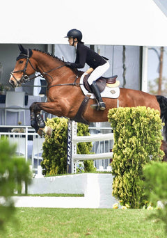 Equestrian rider jumping a horse while wearing Espoir show jacket, showcasing athletic fit, flexible fabric, and elegant competition styling
